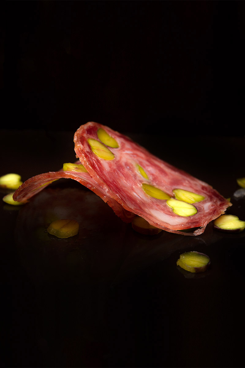 Fetta di mortadella al pistacchio su fondo nero