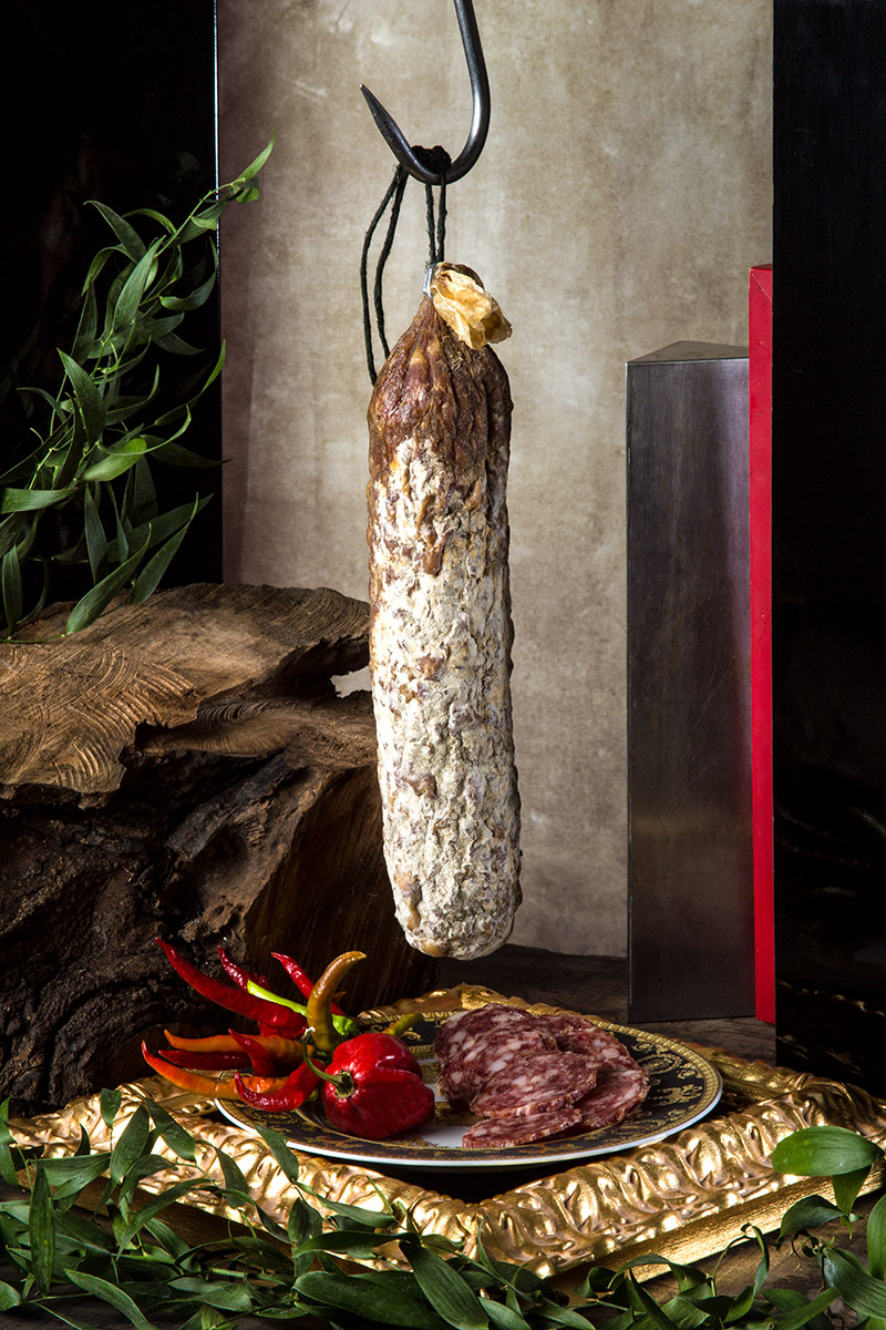 Salame appeso con peperoncini e fette su piatto dorato