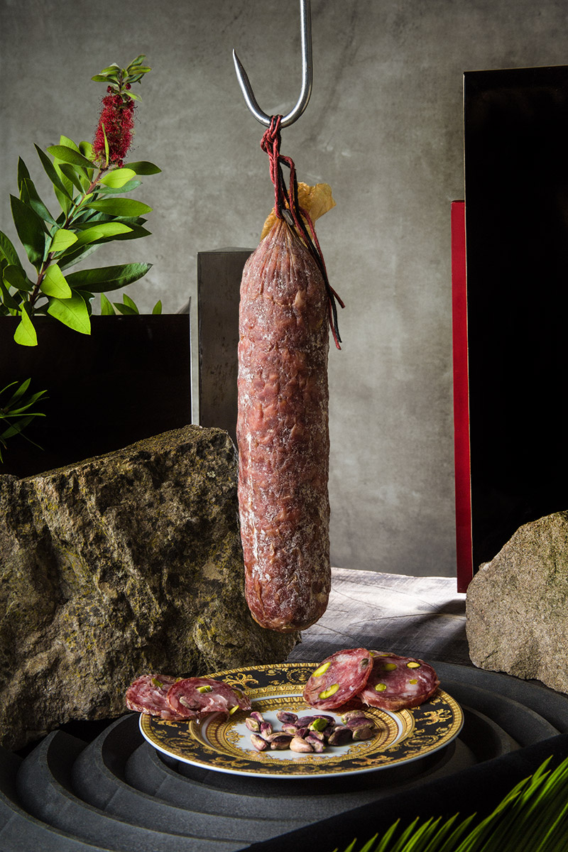 Salame appeso al gancio, fette su piatto decorato